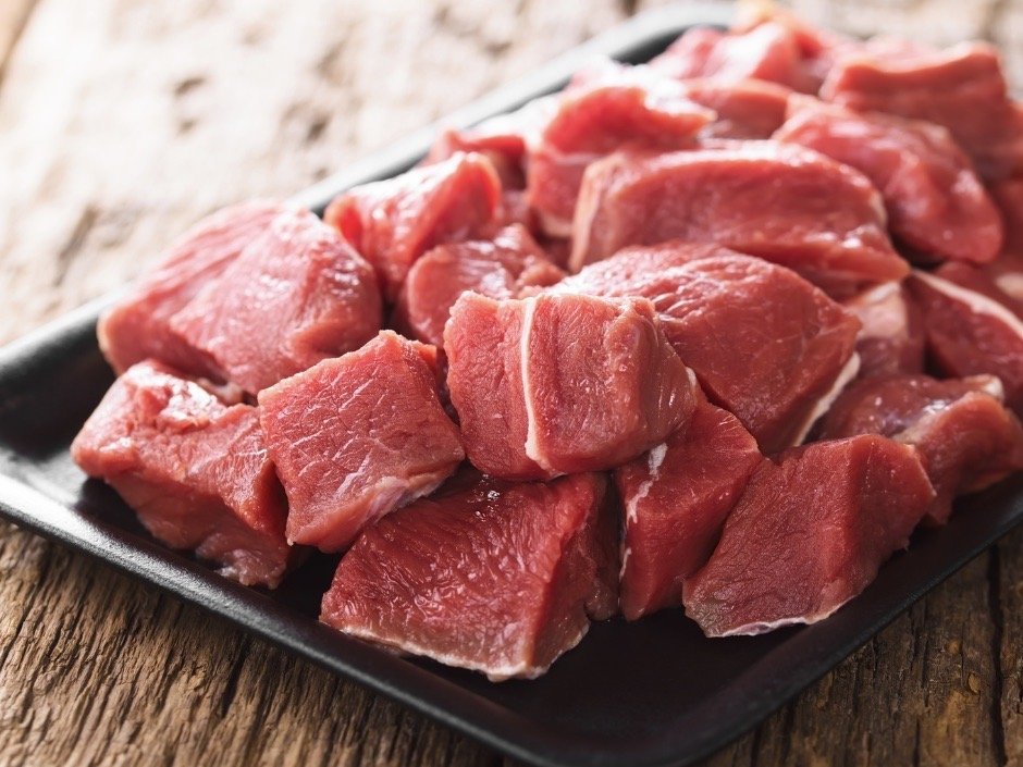 Fresh cuts of red meat displayed on a black platter, ideal for stews or grilling, showcasing a variety of tender pieces with rich color and marbling.